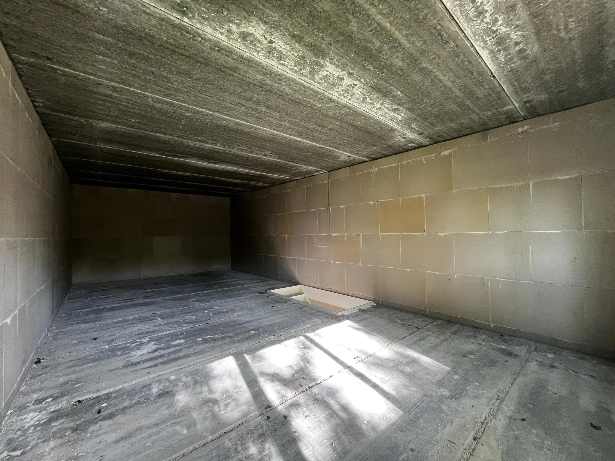 Lege betonnen ruimte in aanbouw aan de Broekdijk West 19-4, met ongeverfde muren en een open gat in de vloer.